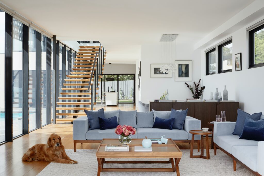 Pet-friendly modern living room in a Calgary home, featuring a cozy sofa, a welcoming dog, and an elegant staircase, highlighting the blend of comfort and style in Calgary's residential spaces.